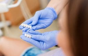 doctor hands showing a sample of dental crowns to a patient